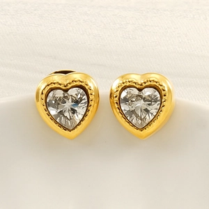 Eleganti orecchini a cuore d'oro con zirconi scintillanti su un piatto di ceramica