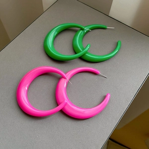 Detail of chunky C-shape hoop earrings in vibrant neon green and hot pink resin finish