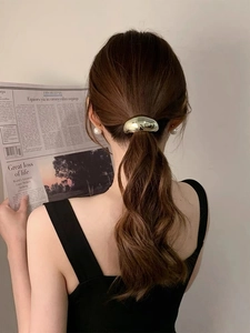 Dettaglio di un elastico per capelli in metallo dorato lucido in stile francese