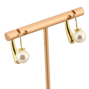 Boucles d'oreilles rétro dorées avec grandes perles blanches sur un support de studio