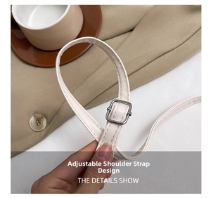 Close-up of adjustable white leather shoulder strap with silver buckle on a handbag
