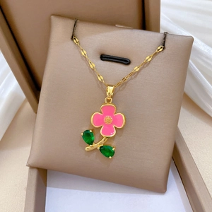 Gros plan d'un collier doré de luxe avec pendentif fleur rose sur un coussin à bijoux