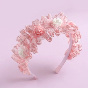 Detailed view of pink floral lace headband with realistic fabric flowers on a soft base