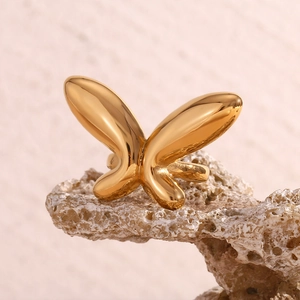 Détail d'une bague papillon en acier inoxydable doré 18 carats sur pierre corail