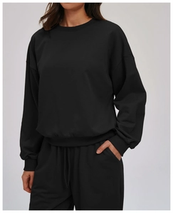 Close-up of black crewneck sweatshirt detail showing ribbed cuffs and premium fabric texture