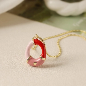 Détail du collier chaîne dorée avec pendentif émail rouge et rose et accent de cœur doré