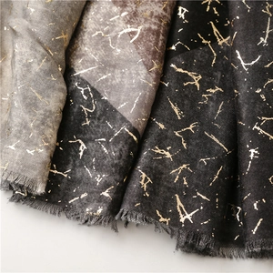 Close-up of thick grey scarf with golden metallic marble pattern and fringe details