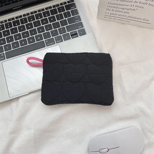 Detail of black quilted sanitary bag with heart patterns and pink zipper puller