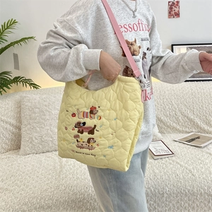 Detail of yellow quilted bag with cartoon dog embroidery and adjustable pink strap