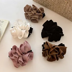 Barrettes bananes en satin aux tons terre pour queue de cheval haute sur surface beige