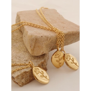 Minimalist gold rose embossed oval pendant necklace on stone background for women