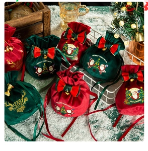 Detail of velvet Christmas drawstring bags with festive bows and golden bells