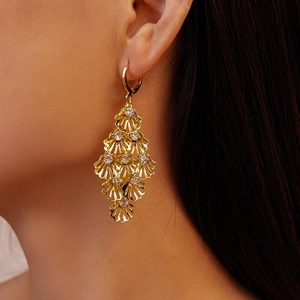 Detail of gold shell tassel earring with hollow diamond design on model
