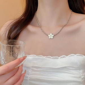Close-up of a silver flower pendant necklace with diamonds on a model's collarbone