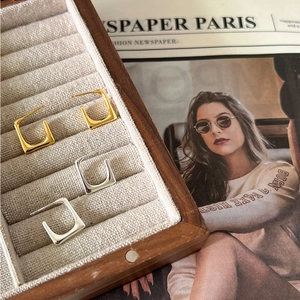 Detail of square geometric 925 silver hoop earrings in gold and silver finish on display