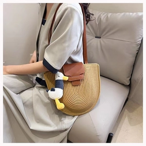 Detail of hand-woven cotton shoulder bag with leather flap and duck charm on model