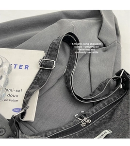 Detail of adjustable strap and dual metal zippers on washed black denim shoulder bag
