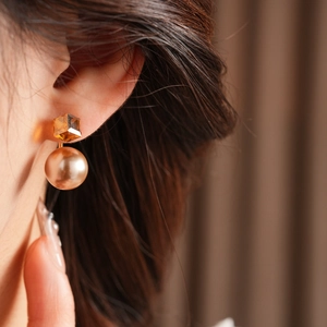Detail of French vintage gold earrings with amber faceted stone and champagne round pearl