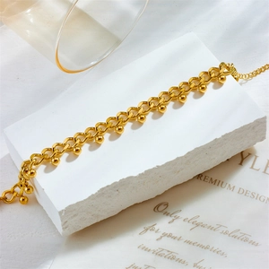 Elegant gold chain bracelet with polished sphere charms on a textured stone base
