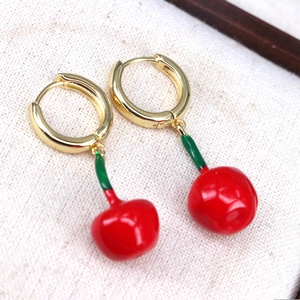 Cute golden hoop earrings featuring vibrant red cherry pendants with green leaves