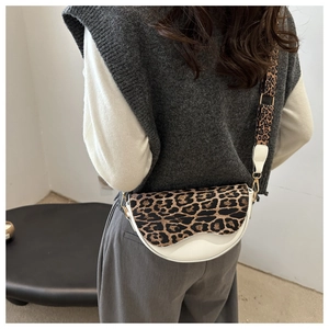 Detail of leopard print saddle bag with wide shoulder strap worn by a model