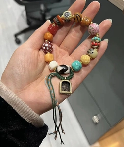 Detailed view of Tibetan Dzi agate bracelet with turquoise, amber, and gold charms