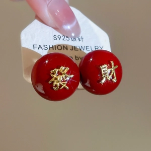 Gros plan de boucles d'oreilles perles rouges avec caractères chinois dorés en argent