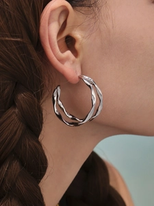 Gros plan de boucles d'oreilles créoles doubles torsadées en acier inoxydable argenté