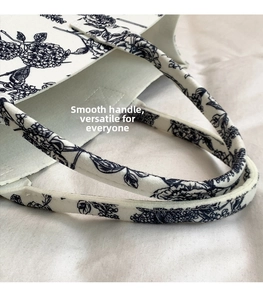 Detailed close-up of reinforced handles on a blue and white floral printed felt tote bag