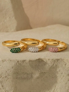 Detailed view of three gold drop rings with emerald, white and pink zircons on stone