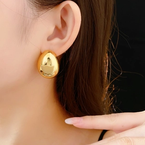 Gros plan d'une boucle d'oreille goutte d'eau dorée polie sur l'oreille d'un modèle