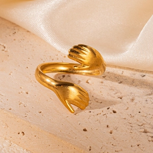 Detailed view of the 18K gold hug ring on a beige silk and stone background