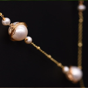 Macro shot of natural freshwater pearl with gold wire wrapping detail on necklace