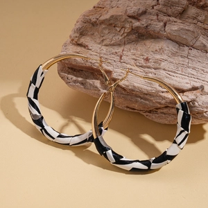 Detail of leopard print leather wrapped gold hoops with textured weaving and silver needle