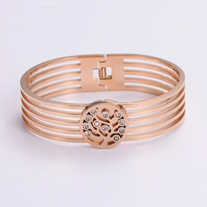 Macro detail of rose gold hollow bangle featuring a sparkling tree of life emblem