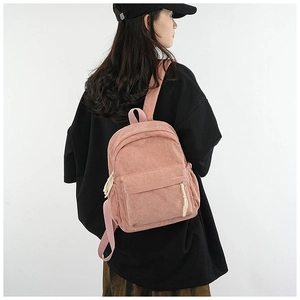 Model wearing a pink corduroy backpack against white background for a soft academic look