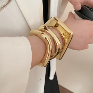 Detail of chunky irregular geometric gold bangles with a high-polished mirror finish