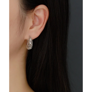 Macro shot of silver hollow patterned teardrop earrings worn by a female model