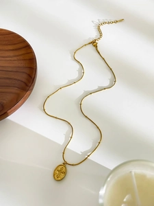 Detail of vintage gold cross pendant necklace with snake bead chain and lobster clasp