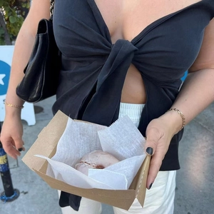 Close-up of a black deep V-neck tie-front crop top with large bow detail and gold bracelets