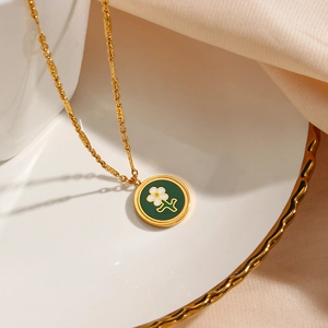 Gold 18K plated stainless steel necklace with green enamel flower pendant on porcelain