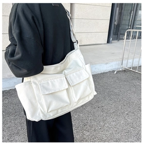 Detailed back view of a white canvas crossbody bag with large pockets on a model outdoors