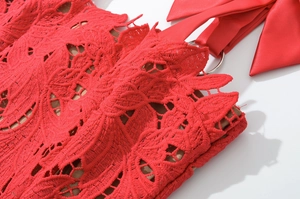 Detailed macro view of red lace dress with intricate floral embroidery and satin bow