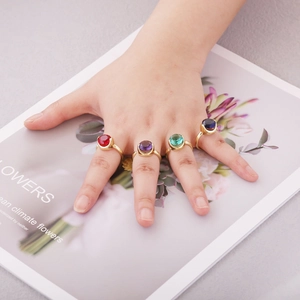 Top view of gold-plated open rings featuring faceted red, purple, green, and blue zircons