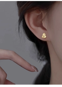 Macro shot of gold-plated calabash earring with textured surface on a female earlobe