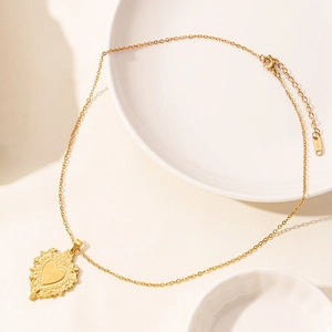Detailed macro view of heart pendant in gold-plated stainless steel with relief texture