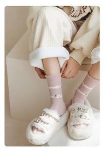 Pink cotton crew socks with white stripes and floral print worn with fuzzy slippers