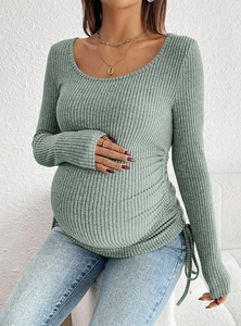 Detail eines salbeigrünen Umstandsstrickoberteils mit seitlichem Kordelzug für den Bauch