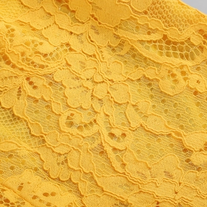 Dettaglio macro del tessuto in pizzo giallo con intricati motivi floreali e ricami