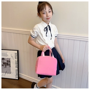 Pink canvas insulated lunch bag with zipper and handle held by school girl